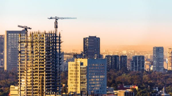 Aerial view of construction cranes and skyscrapers in Ciudad de México at sunset.